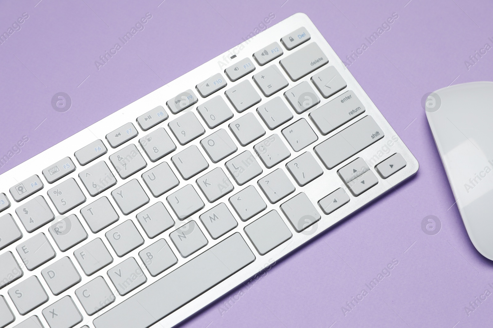 Photo of White wireless keyboard and mouse on violet background, above view