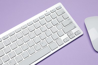 Photo of White wireless keyboard and mouse on violet background, above view