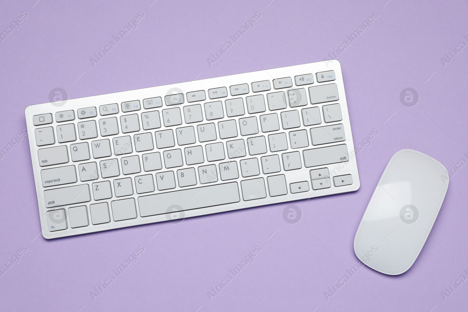 Photo of White wireless keyboard and mouse on violet background, top view