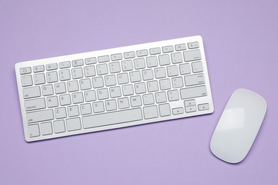 Photo of White wireless keyboard and mouse on violet background, top view