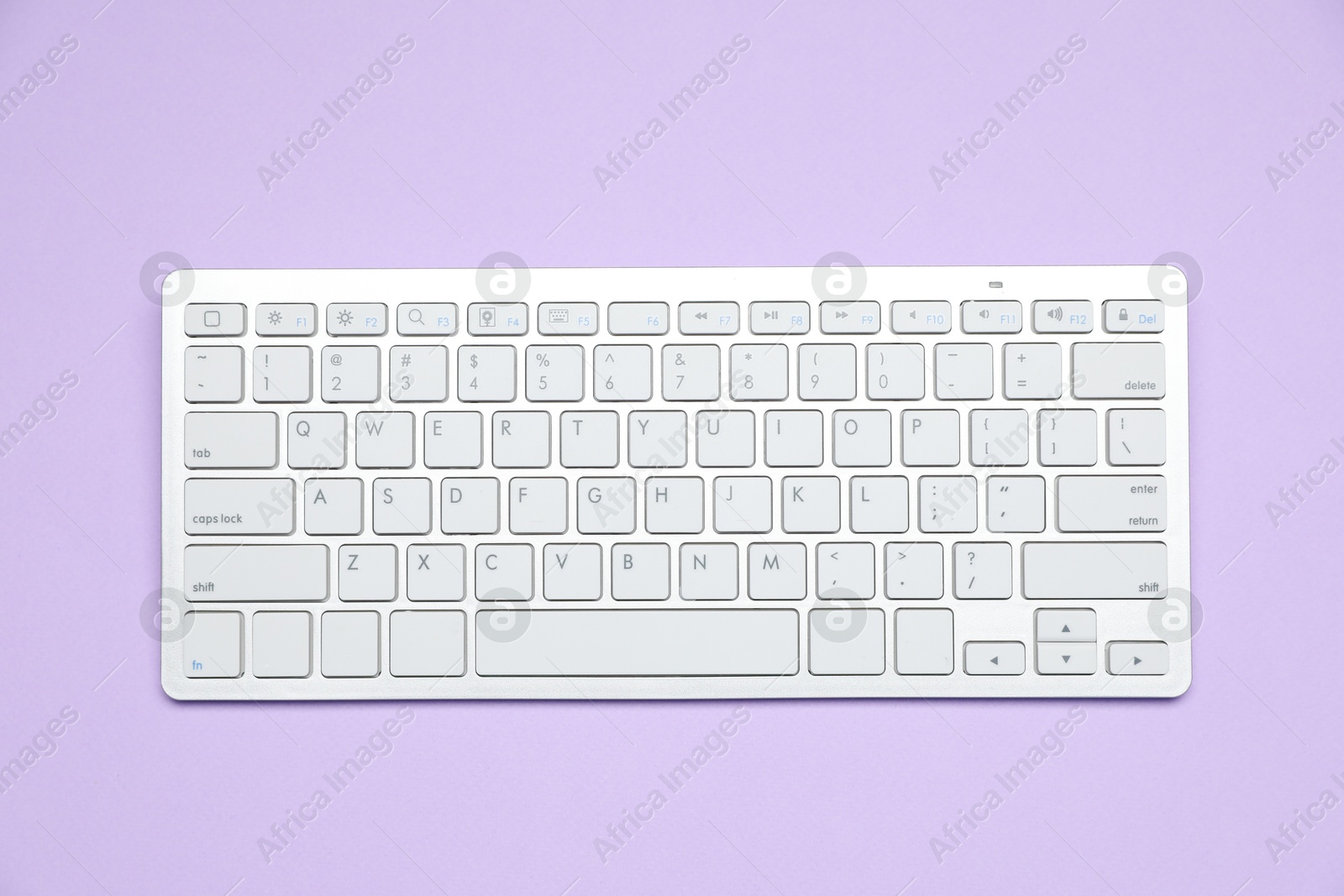 Photo of White wireless keyboard on violet background, top view