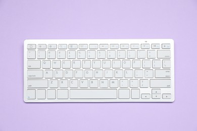 Photo of White wireless keyboard on violet background, top view