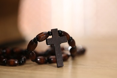 Photo of Rosary with wooden cross on table, closeup. Space for text