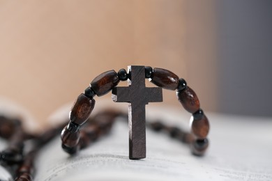 Photo of Rosary with wooden cross on Holy Bible, closeup