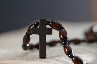 Photo of Rosary with wooden cross on Holy Bible, closeup