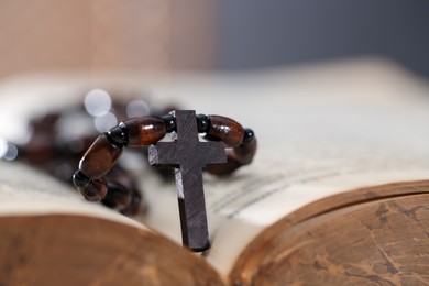 Photo of Rosary with wooden cross on Holy Bible, closeup
