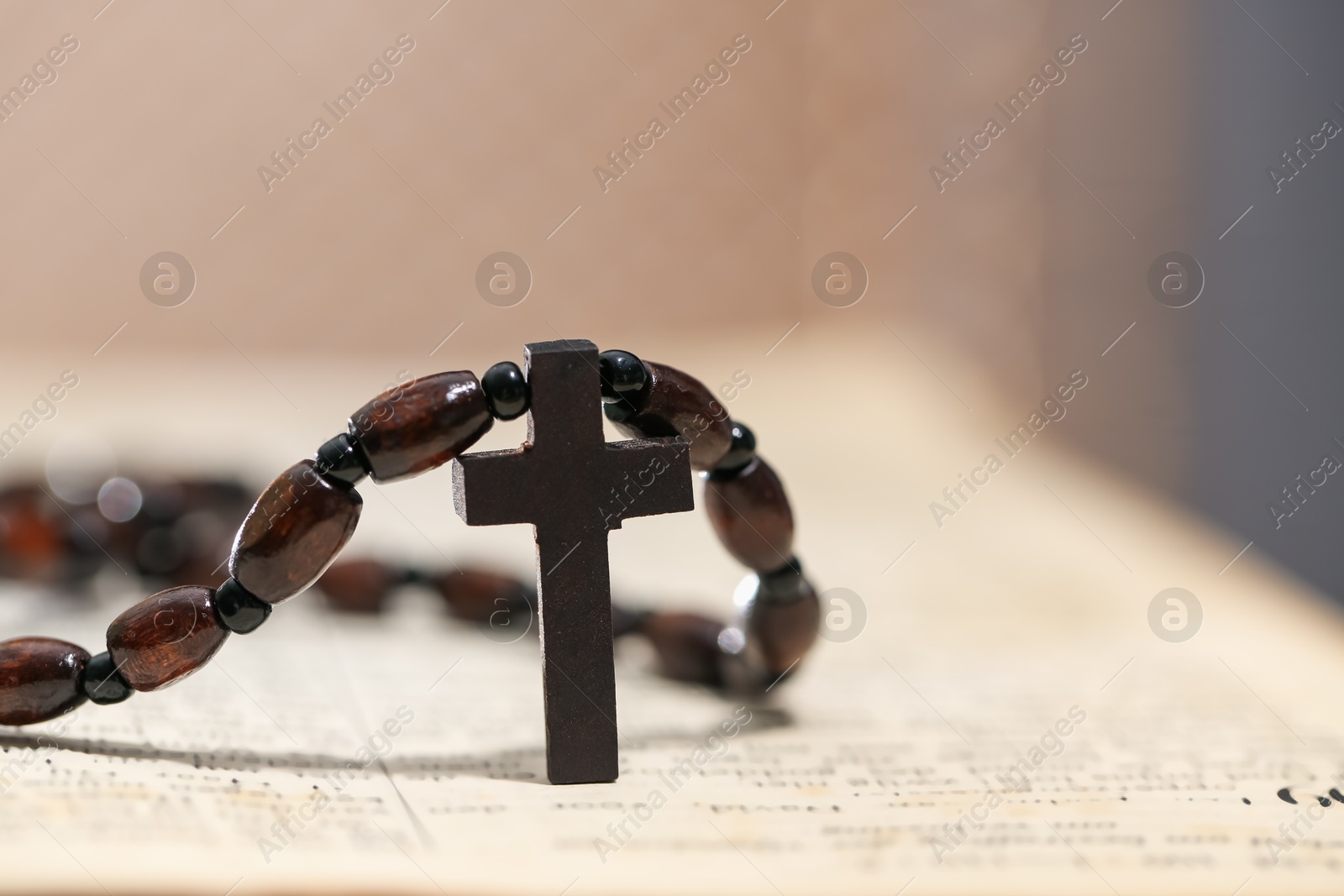 Photo of Rosary with wooden cross on Holy Bible, closeup. Space for text