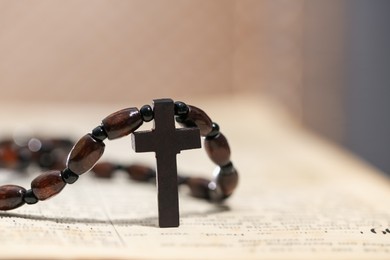 Photo of Rosary with wooden cross on Holy Bible, closeup. Space for text
