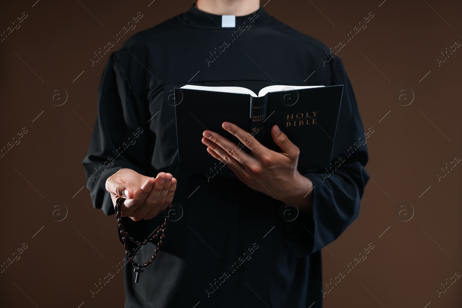 Photo of Priest with Holy Bible and rosary on brown background, closeup