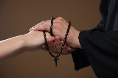 Photo of Priest and woman holding hands on brown background, closeup