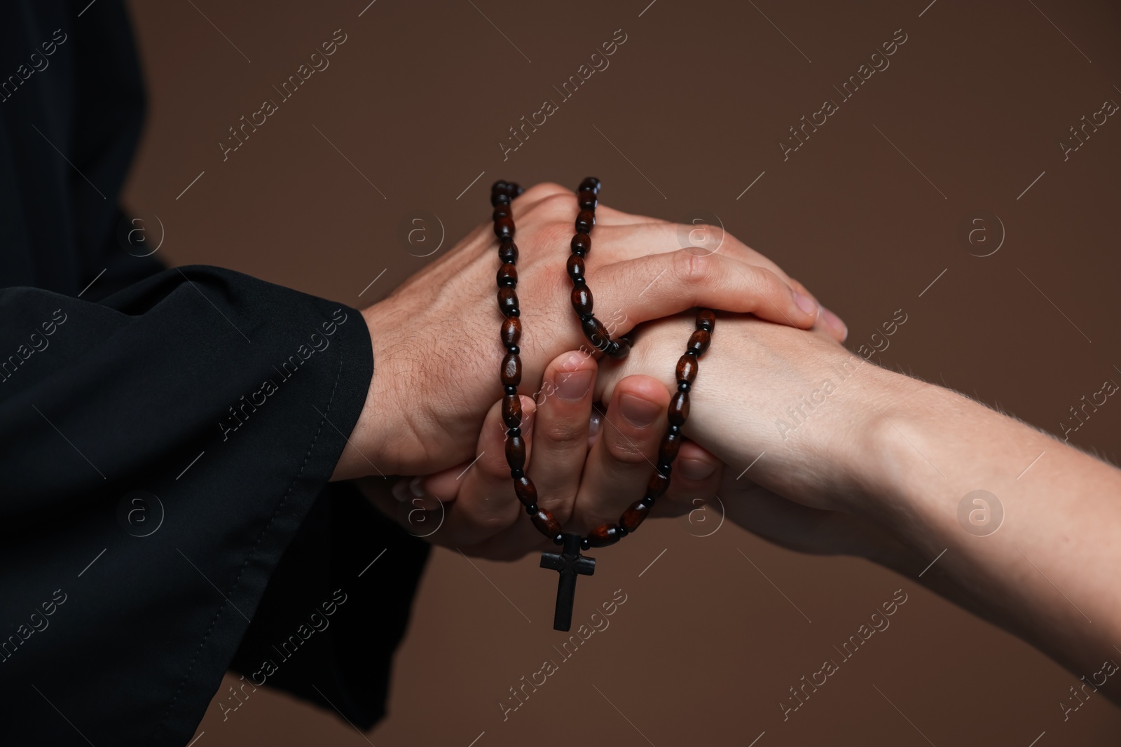 Photo of Priest and woman holding hands on brown background, closeup