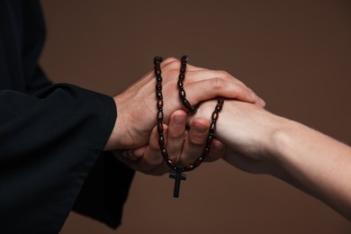 Photo of Priest and woman holding hands on brown background, closeup