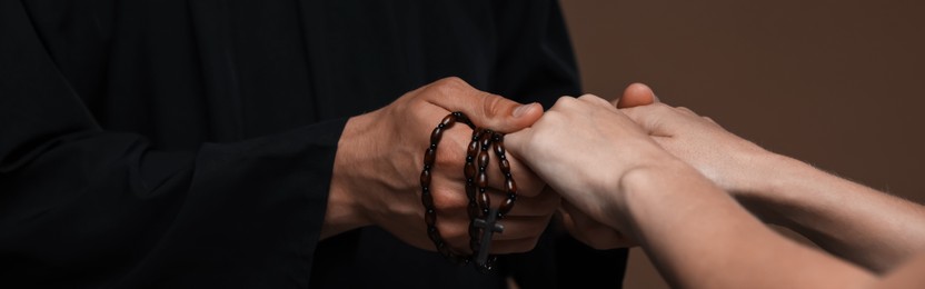 Photo of Priest and woman holding hands on brown background, closeup