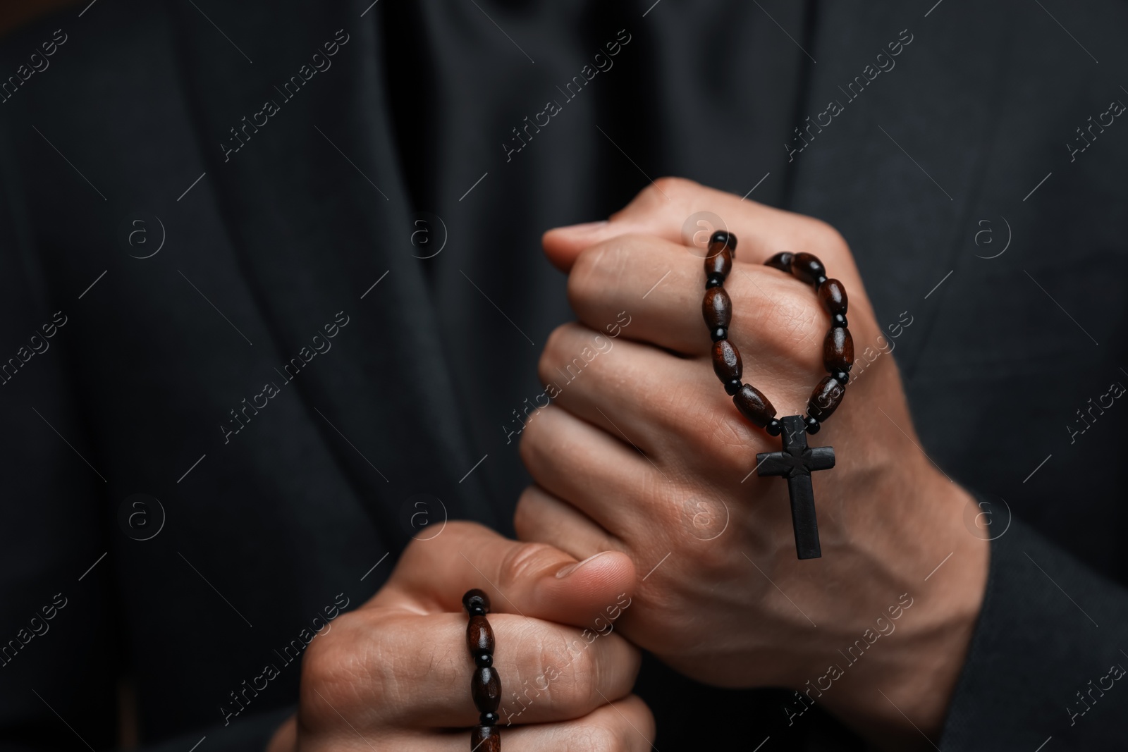 Photo of Priest holding rosary with cross, closeup view