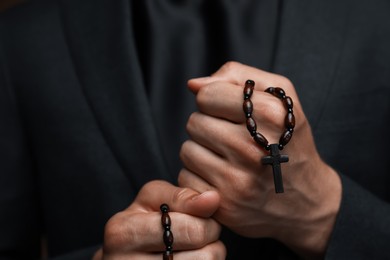 Photo of Priest holding rosary with cross, closeup view