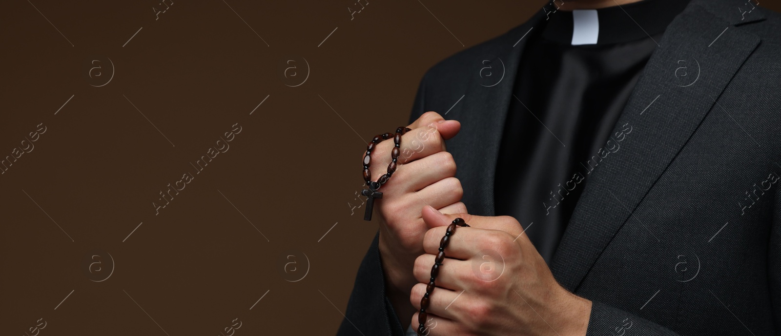 Photo of Priest with rosary on brown background, closeup. Space for text