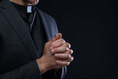 Photo of Priest praying on black background, closeup. Space for text