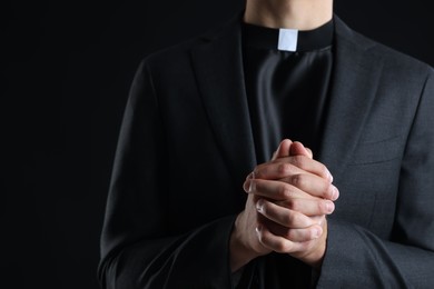 Photo of Priest praying on black background, closeup view