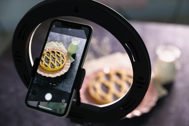 Photo of Shooting tasty pie and milk with smartphone in studio, selective focus. Professional food photography