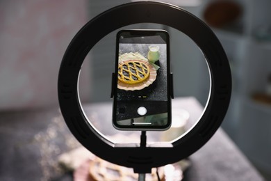 Photo of Shooting tasty pie and milk with smartphone in studio, selective focus. Professional food photography