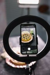 Photo of Shooting tasty pie and milk with smartphone in studio, selective focus. Professional food photography