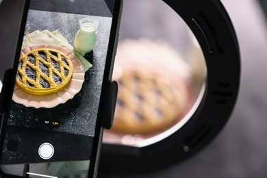 Photo of Shooting tasty pie and milk with smartphone in studio, selective focus. Professional food photography