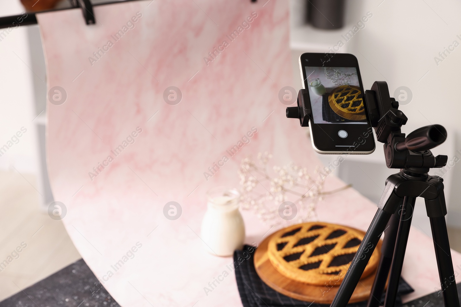 Photo of Shooting tasty pie and milk with smartphone in studio, selective focus. Professional food photography