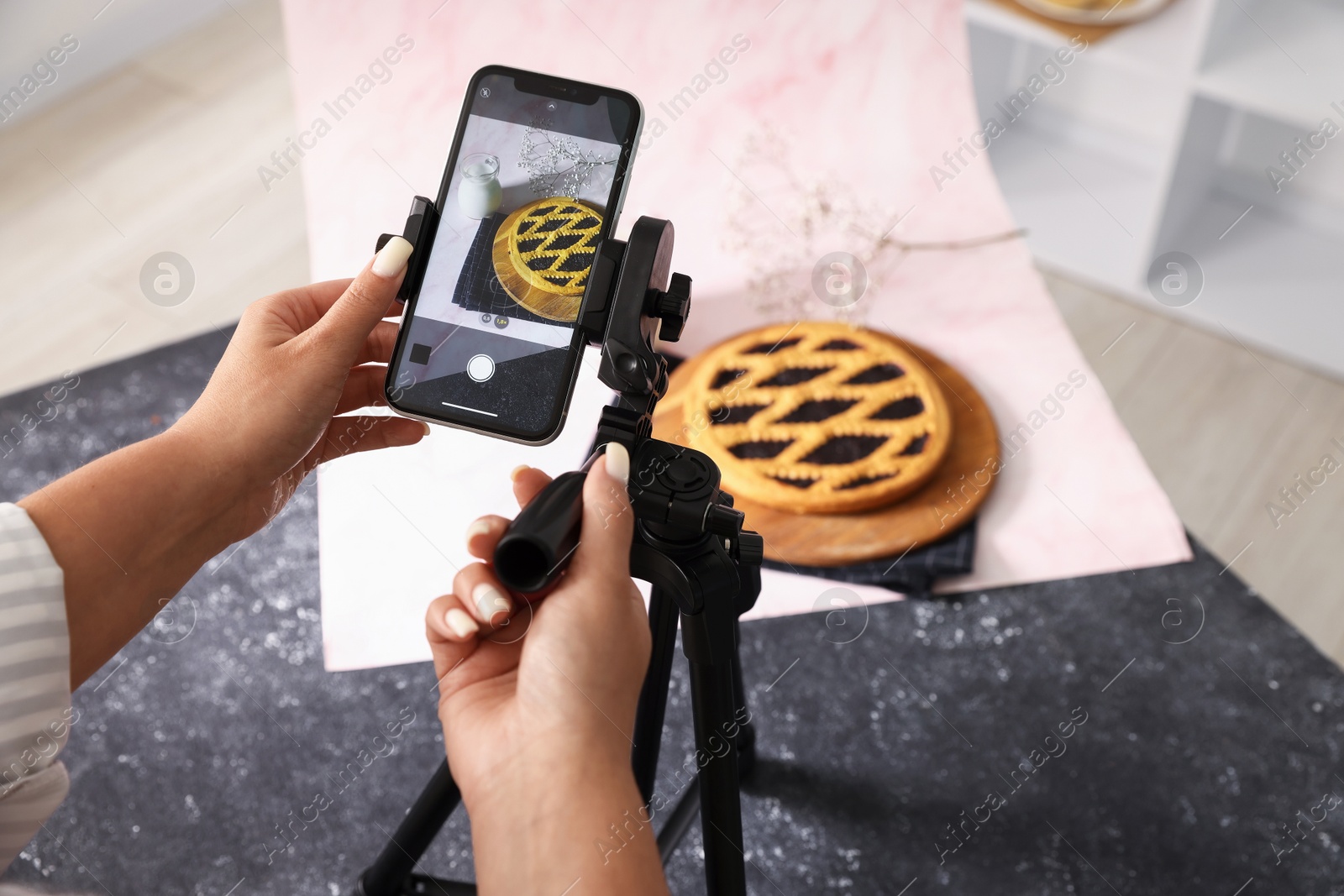 Photo of Woman taking picture of tasty pie and milk in studio, above view. Professional food photography