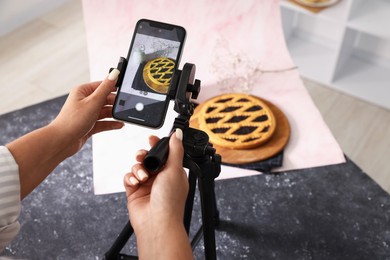 Photo of Woman taking picture of tasty pie and milk in studio, above view. Professional food photography