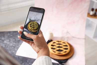 Photo of Woman taking picture of tasty pie and milk in studio, selective focus. Professional food photography