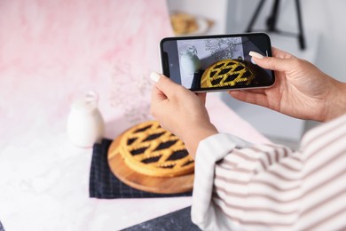 Photo of Woman taking picture of tasty pie and milk in studio, selective focus. Professional food photography
