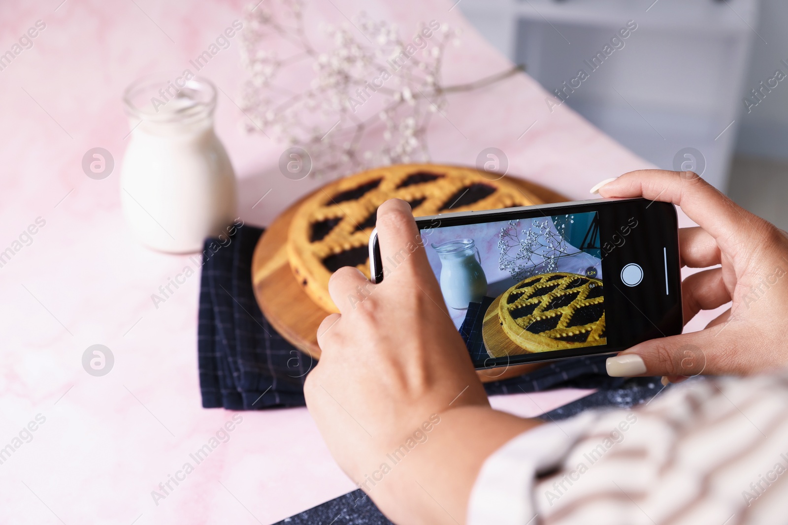 Photo of Woman taking picture of tasty pie and milk in studio, selective focus. Professional food photography