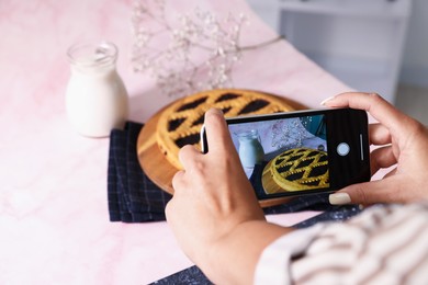 Photo of Woman taking picture of tasty pie and milk in studio, selective focus. Professional food photography