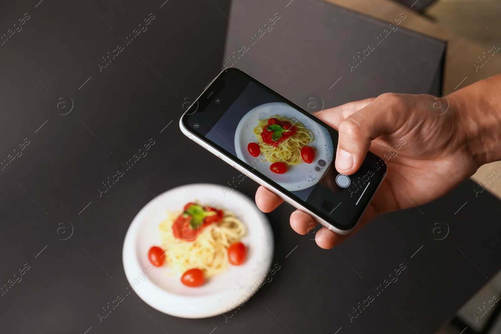 Photo of Man taking picture of pasta with smartphone in studio, closeup. Professional food photography