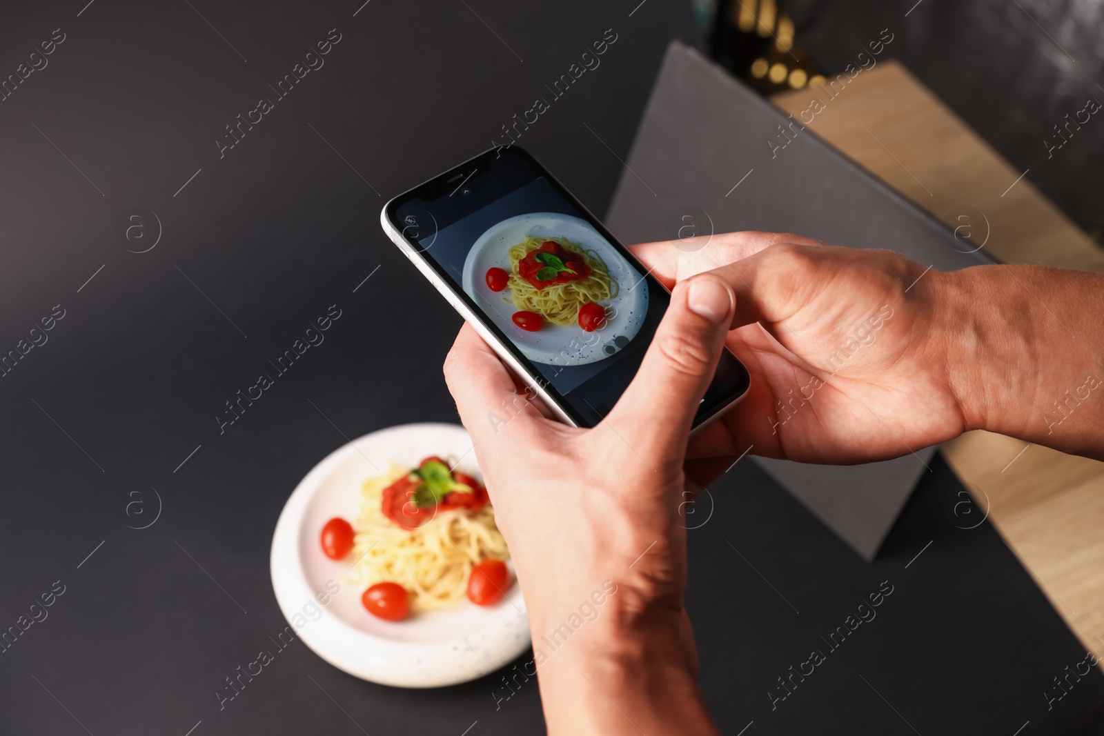 Photo of Man taking picture of pasta with smartphone in studio, closeup. Professional food photography