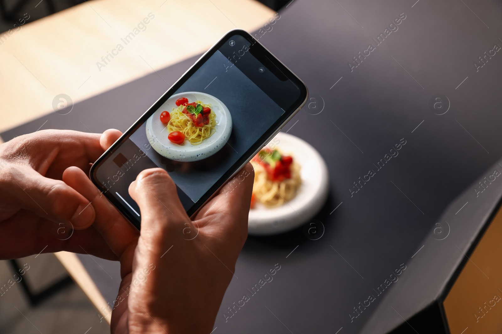Photo of Man taking picture of pasta with smartphone in studio, closeup. Professional food photography