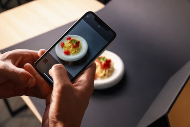 Photo of Man taking picture of pasta with smartphone in studio, closeup. Professional food photography