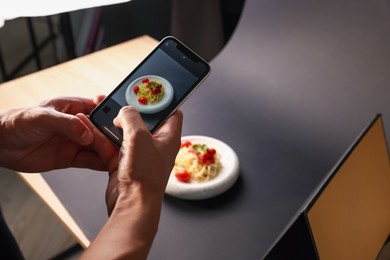Photo of Man taking picture of pasta with smartphone in studio, closeup. Professional food photography
