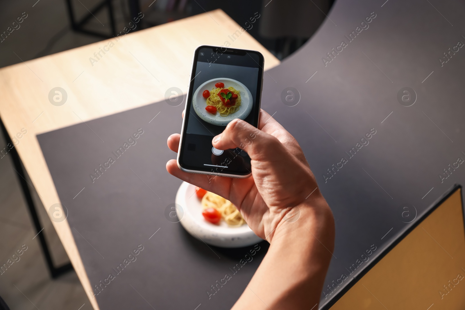 Photo of Man taking picture of pasta with smartphone in studio, closeup. Professional food photography
