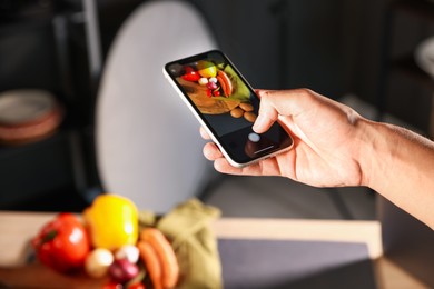 Photo of Woman taking picture of vegetables with smartphone in studio, closeup. Professional food photography