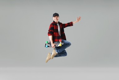 Photo of Happy young man with penny board jumping on light grey background