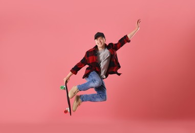 Photo of Happy young man with penny board jumping on pink background