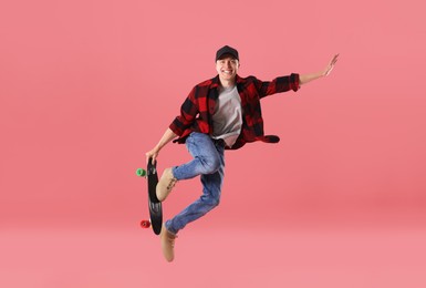Photo of Happy young man with penny board jumping on pink background