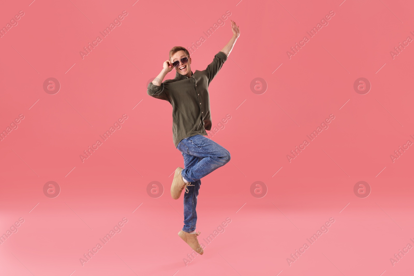 Happy young man jumping on pink background Photo of Happy young man jumping on pink background