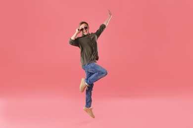 Photo of Happy young man jumping on pink background