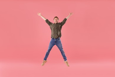 Photo of Happy young man jumping on pink background