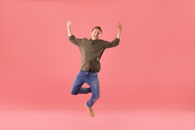 Photo of Happy young man jumping on pink background