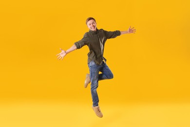 Photo of Happy young man jumping on orange background