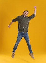 Photo of Happy young man jumping on orange background
