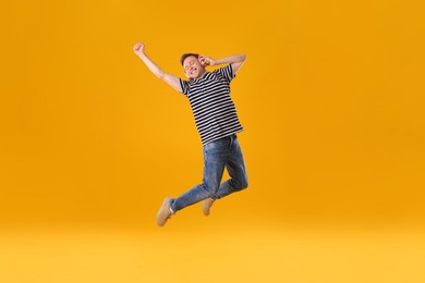 Photo of Happy young man with headphones jumping on orange background